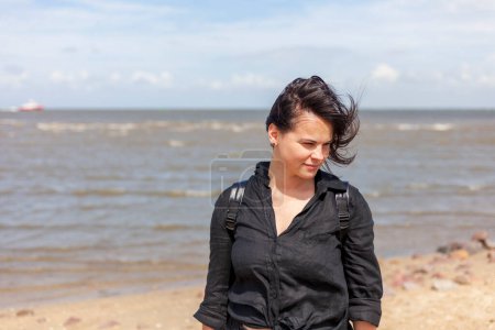 Porträt einer schönen brünetten Frau in schwarzer Kleidung auf dem Hintergrund des Meeres