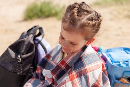 Kleines Mädchen mit Rucksack am Strand im Sommer. Zurück zur Schule.