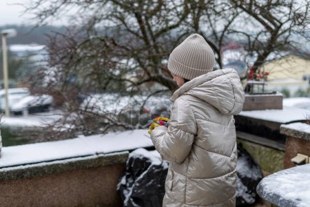 Little girl with a bouquet of flowers on the street in winter