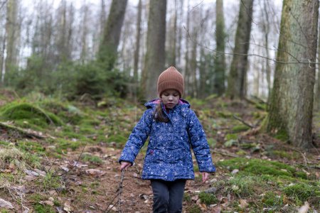 Linda niña caminando en el bosque en un frío día de invierno
