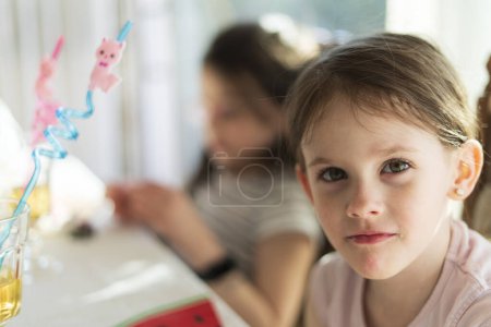 Portrait of cute little girl with her sister in background at home