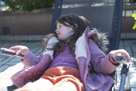 Kleines Mädchen sitzt mit Handy in der Hand auf einer Bank