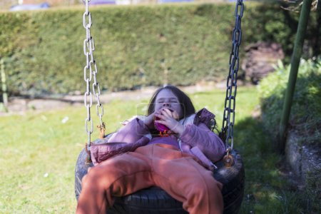 Petite fille s'amuser sur une balançoire dans le parc par une journée ensoleillée