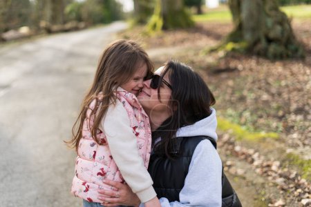 Mother and daughter kissing on the road in the countryside. Selective focus.