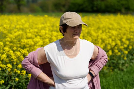 Elderly woman standing in a field of blooming rapeseed
