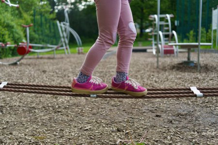 Las piernas de los niños pequeños van a lo largo de una cuerda en un campo de deportes para niños en el verano