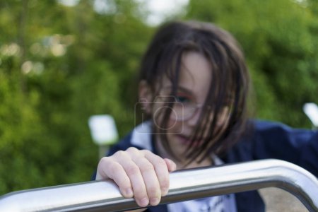Petite fille écolière en lunettes jouit sur une aire de jeux d'été