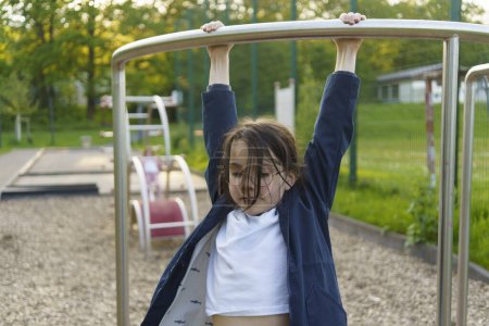 Little girl Schoolgirl in glasses enjoys on a summer playground