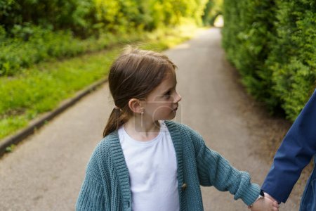 Two little girls holding hands along the street walking