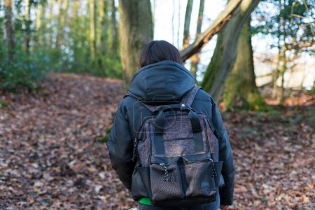 Vista trasera de una mujer con una mochila en medio de un bosque