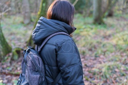 Rückenansicht einer Frau mit Rucksack im Wald. Rückseite.