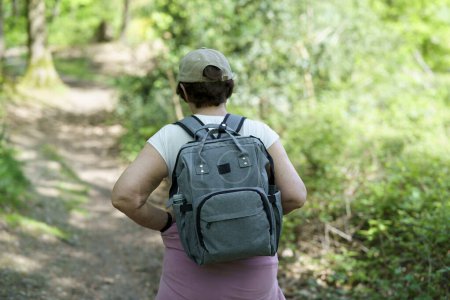 Rear view of a woman with backpack walking on a forest trail
