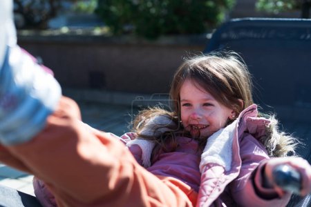 Ein kleines Mädchen mit geschminktem Gesicht liegt lächelnd auf einer Sonnenbank im Hinterhof. Glückskonzept für Kinder
