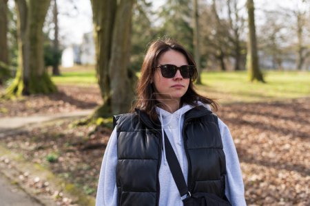 Dark-haired middle-aged girl in sunglasses in an autumn park