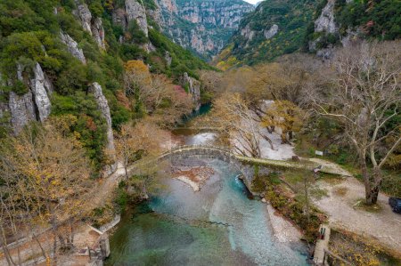 Photo for Top down aerial view  of the  old stone bridge in Klidonia  during fall season.  This arch bridge was built in 1853 and it is situated on the river of Voidomatis in  Zagori, Epirus Greece. - Royalty Free Image
