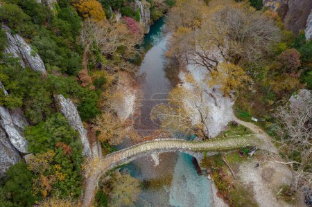 Photo for Top down aerial view  of the  old stone bridge in Klidonia  during fall season.  This arch bridge was built in 1853 and it is situated on the river of Voidomatis in  Zagori, Epirus Greece. - Royalty Free Image