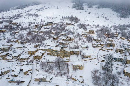 Photo for Aerial view of traditional architecture  with  stone buildings covered  with snow  during  winter season in the picturesque village of Nymfaio  Florinas, Greece - Royalty Free Image
