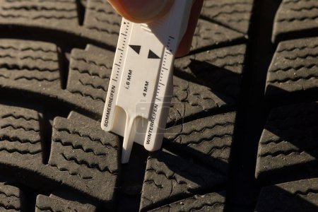Téléchargez les photos : Gros plan de la mesure de la profondeur de la bande de roulement des pneus de voiture pour des raisons de sécurité - en image libre de droit