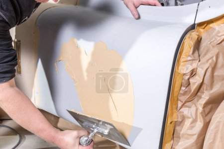Foto de Primer plano del trabajo con una espátula en una superficie imprimada en un coche clásico - Imagen libre de derechos