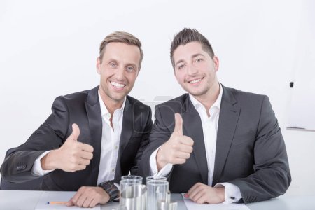 two smiling business men showing thumbs up