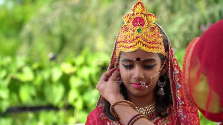 Téléchargez les photos : Une fille portant une robe de tradition pendant la saison festive Navratri. Portrait de jolie petite indienne vêtue d'une robe traditionnelle. Préparation du maquillage pour le festival dandiya - en image libre de droit