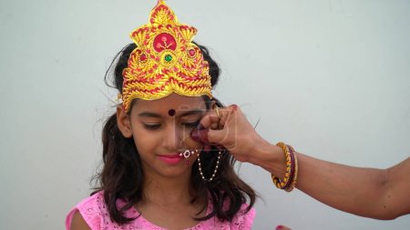 Téléchargez les photos : Une fille portant une robe de tradition pendant la saison festive Navratri. Portrait de jolie petite indienne vêtue d'une robe traditionnelle. Préparation du maquillage pour le festival dandiya - en image libre de droit