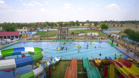 Foto de Parque acuático, toboganes multicolores brillantes con una piscina. Un parque acuático sin gente en un día de verano. Deslizadores Aquapark con piscina. Sikar, Rajastán, India - Imagen libre de derechos