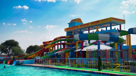 Photo for Water park, bright multi-colored slides with a pool. A water park without people on a summer day. Aquapark sliders with pool. Sikar, Rajasthan, India - Royalty Free Image