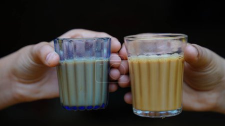 Photo for Milk tea , pouring tea Chai traditional beverage. Two glass of organic ayurvedic or herbal drink India, tea good in winter for immunity boosting. - Royalty Free Image