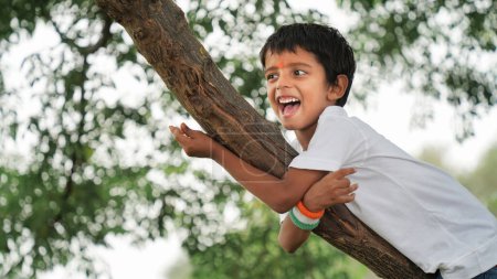 Photo for Little boy smiling and climbing on tree on the occasion of Vijay Diwas - Royalty Free Image