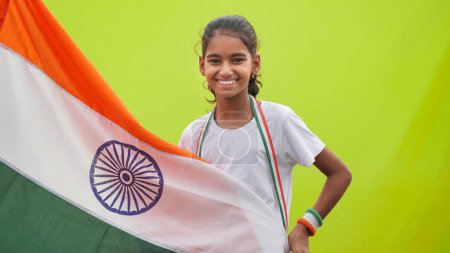Photo for Little Indian girl celebrate the Auspicious Day - Independence Day Or Republic Day, Indian Model. Charming girl standing with a tricolour flag, facing towards the camera - Royalty Free Image