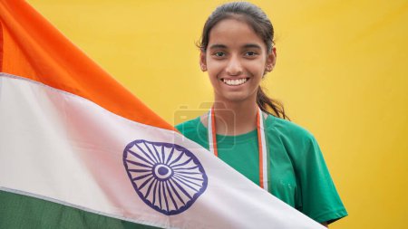 Photo for Little Indian girl celebrate the Auspicious Day - Independence Day Or Republic Day, Indian Model. Charming girl standing with a tricolour flag, facing towards the camera - Royalty Free Image
