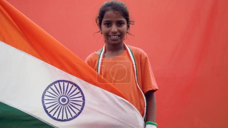 Photo for Little Indian girl celebrate the Auspicious Day - Independence Day Or Republic Day, Indian Model. Charming girl standing with a Indian Flag, facing towards the camera - Royalty Free Image