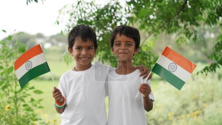 Photo for Cute little boys holding Indian flag in their hands and smiling. Celebrating Independence day or Republic day in India. Kid showing pride of Tiranga - Royalty Free Image