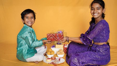 Téléchargez les photos : Heureux frères et sœurs indiens assis ensemble avec plein de boîtes-cadeaux - en image libre de droit