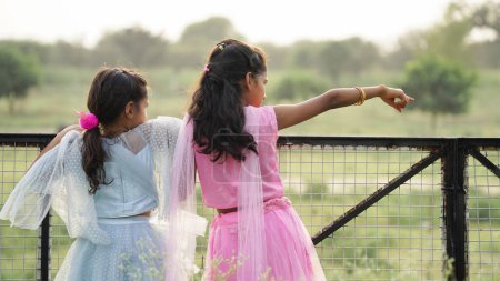 Photo for Portrait of beautiful little indian girls pointing hands while standing in the park - Royalty Free Image