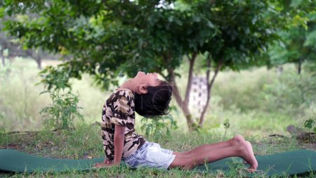 Photo for Portrait of gorgeous kid practicing yoga outdoor. Beautiful child practice yoga asana or doing gymnastic exercises. Little kids meditating in lotus position - Royalty Free Image