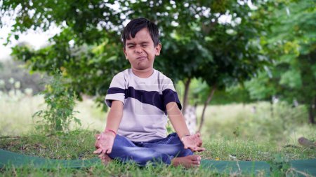 Photo for Portrait of gorgeous kid practicing yoga outdoor. Beautiful child practice yoga asana or doing gymnastic exercises. Little kids meditating in lotus position - Royalty Free Image