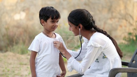 Téléchargez les photos : Jeune médecin indien d'un pédiatre tenant un stéthoscope vérifiant le rythme cardiaque d'un enfant malade. bilan de santé, soins médicaux pour enfants. concept de santé - en image libre de droit