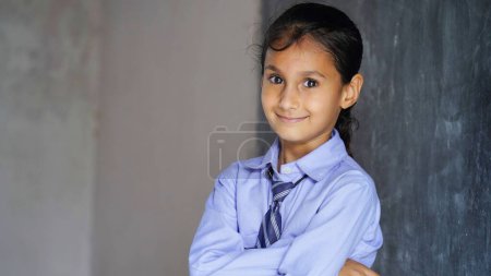 Photo for Happy Indian school girl child standing  in front of black chalkboard background. Education Concept or Back to School - Royalty Free Image