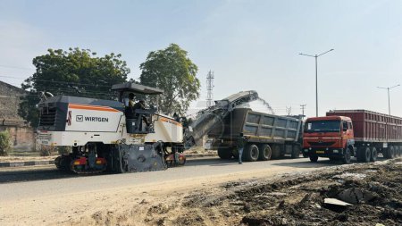 Téléchargez les photos : Le chantier de construction pose une nouvelle chaussée de route asphaltée. Travailleur utilisant une machine de revêtement d'asphalte pendant les travaux de construction et de réparation de routes. Sikar, Rajasthan, Inde - février 2024 - en image libre de droit