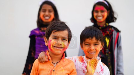 Téléchargez les photos : Heureux mignon souriant regardant les enfants jouer avec des peintures dans leurs doigts. Holi Festival des couleurs. Inde Festival des couleurs. - en image libre de droit