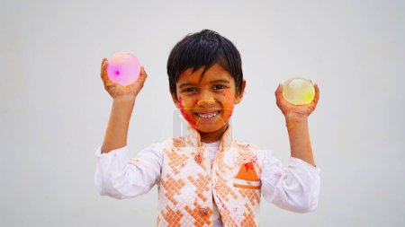 Foto de Niños indios felices jugando colores, sonriendo con colores en la cara o niños asiáticos celebrando Holi. Concepto para el festival indio Holi. Niños brillantes untados en polvo de color - Imagen libre de derechos