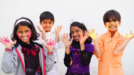 Téléchargez les photos : Joyeux mignon sourire petits enfants indiens montrant leurs mains colorées ou l'impression de la paume ou jouer holi festival avec des couleurs - en image libre de droit