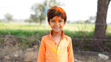 Foto de Niños indios felices jugando colores, sonriendo con colores en la cara o niños asiáticos celebrando Holi. Concepto para el festival indio Holi. Niños brillantes untados en polvo de color - Imagen libre de derechos