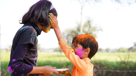 Téléchargez les photos : Enfants couverts de poudre colorée pendant le festival de Holi. heureux mignon asiatique enfants célébrer indien holi festival avec coloré peinture poudre sur visages et corps - en image libre de droit