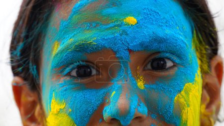 Foto de Chico soplando polvo de color holi de la mano durante la celebración del festival Holi - Concepto de niños pequeños divirtiéndose jugando holi durante la fiesta - Imagen libre de derechos
