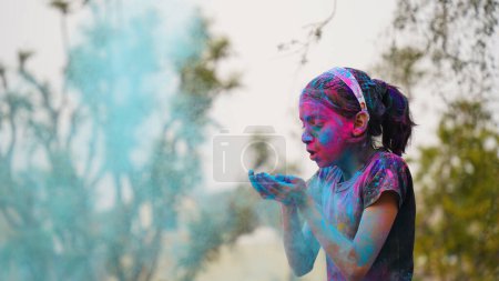 Photo for Happy Indian friends or kids celebrating the Hindu festival of Holi by applying colors to each other, best friends. Female siblings holding a plate with different shades of Gulal - Royalty Free Image