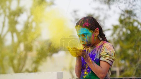 Foto de Felices amigos indios o niños celebrando el festival hindú de Holi aplicando colores el uno al otro, los mejores amigos. Hermanos femeninos sosteniendo un plato con diferentes tonos de Gulal - Imagen libre de derechos