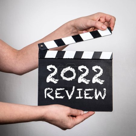2022 Review. Female hands holding movie clapper. Business concept.